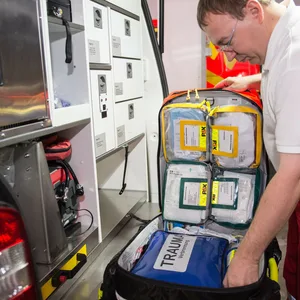 Mitarbeiter des Rettungsdienstes öffnet den Notfallrucksack im Rettungswagen
