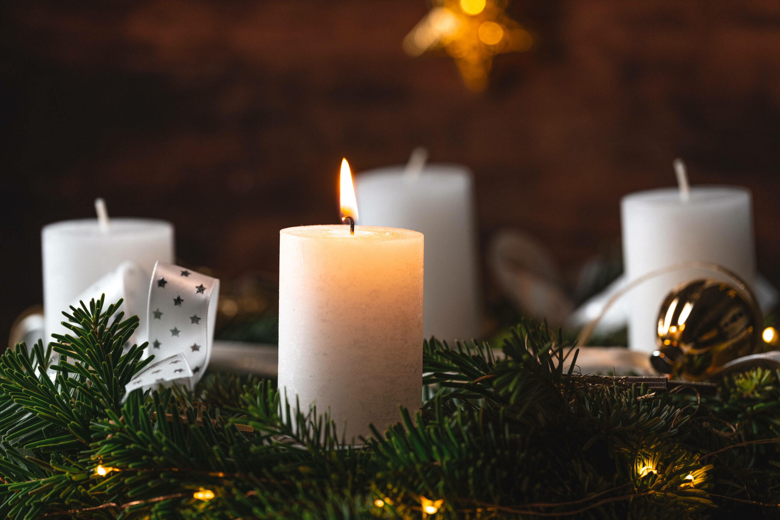 Eine Kerze brennt zum 1. Advent auf einem festlichen Adventskranz zur Adventszeit.