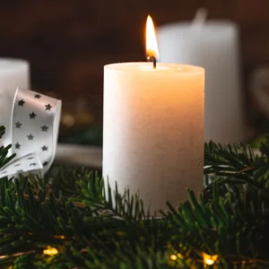 Eine Kerze brennt zum 1. Advent auf einem festlichen Adventskranz zur Adventszeit.