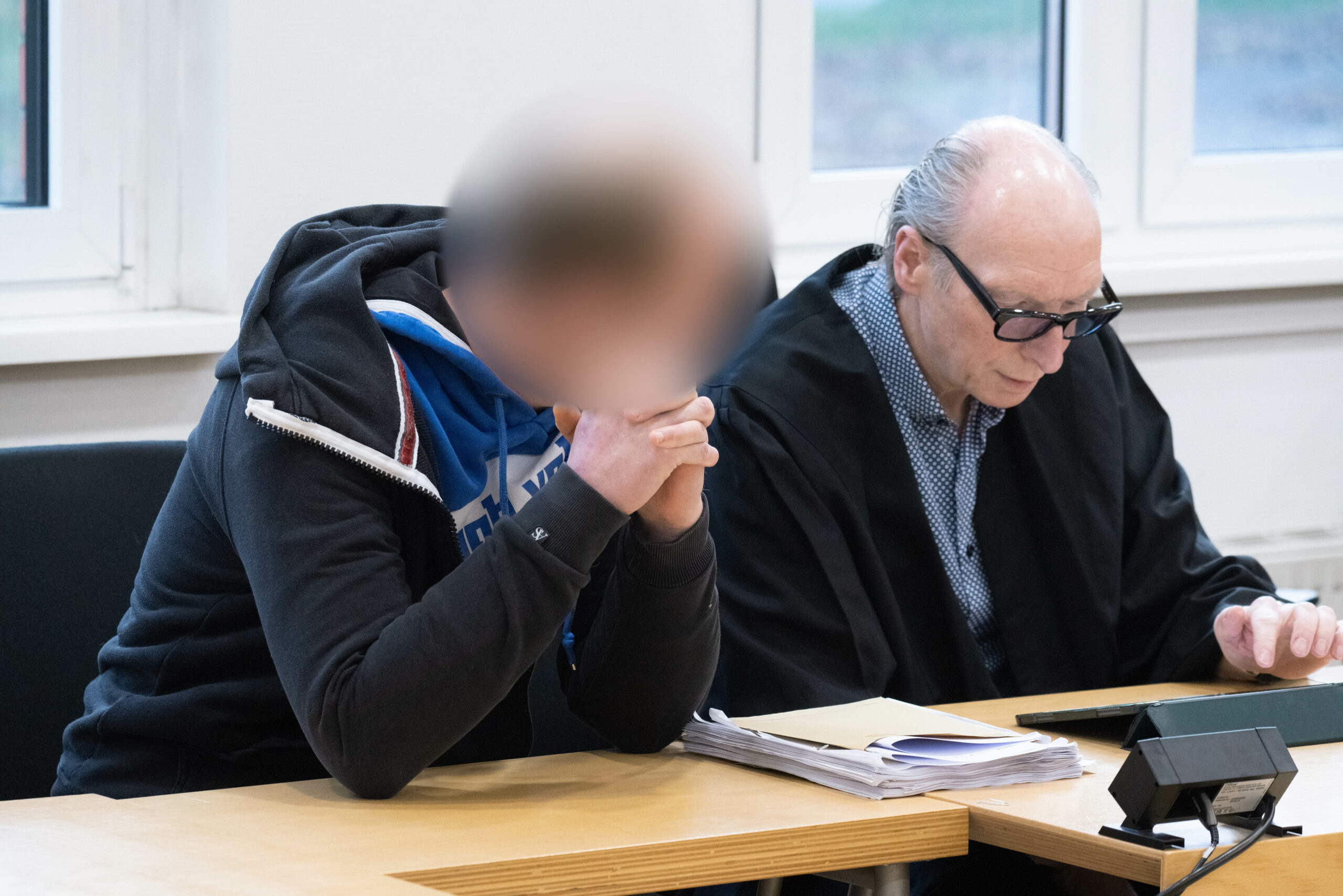 Der Angeklagte (l.) sitzt im Verhandlungssaal im Landgericht Stralsund neben seinem Pflichtverteidiger.