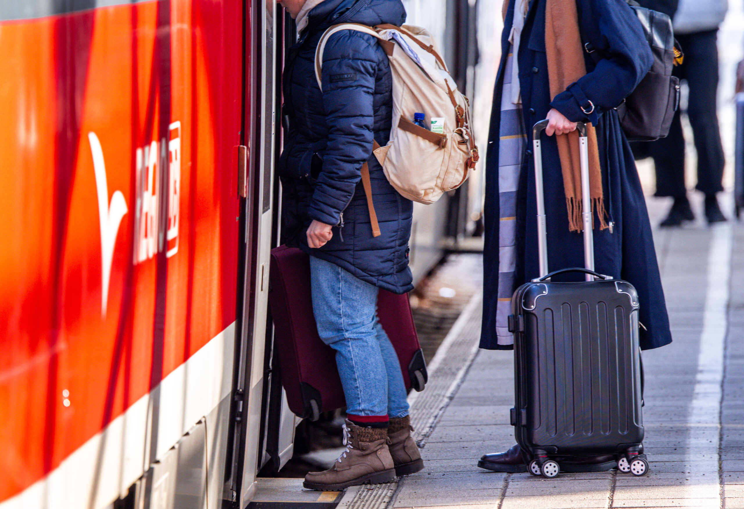 Passagiere mit Koffern steigen in eine Regionalbahn nach Rostock ein.