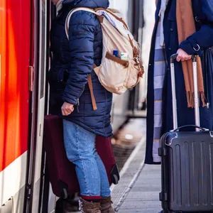 Passagiere mit Koffern steigen in eine Regionalbahn nach Rostock ein.