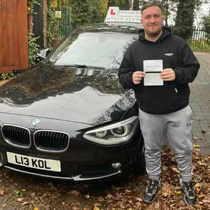 Luke Littler posiert mit seinem Führerschein vor dem Fahrschul-Auto