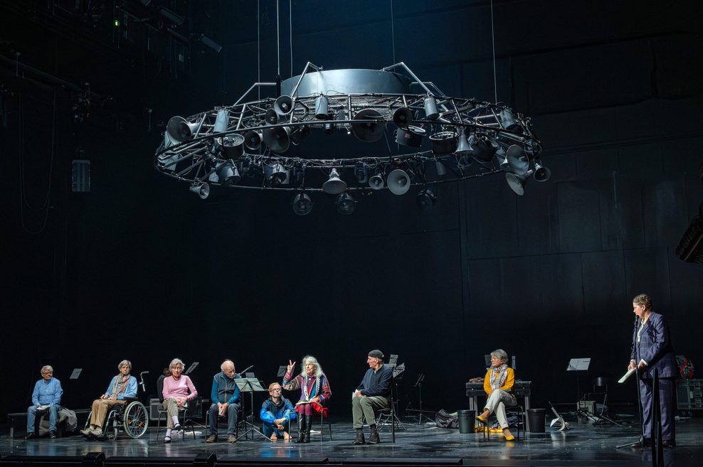 Dunkle Bühne, auf der die Personen sitzen