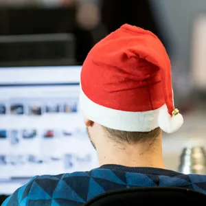 Ein Mann sitzt mit Weihnachtsmütze im Büro.