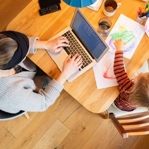 Eine Frau arbeitet im Homeoffice mit Kind.