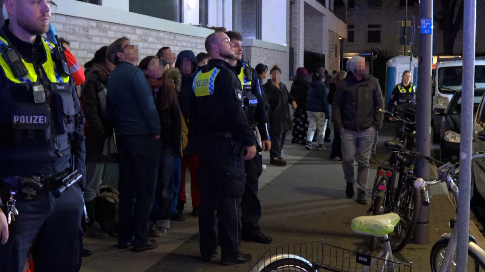 Anwohner und Polizisten verfolgen die Löscharbeiten, nachdem das Gebäude evakuiert wurde.