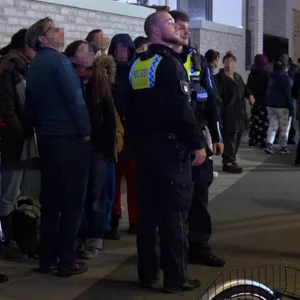 Anwohner und Polizisten verfolgen die Löscharbeiten, nachdem das Gebäude evakuiert wurde.