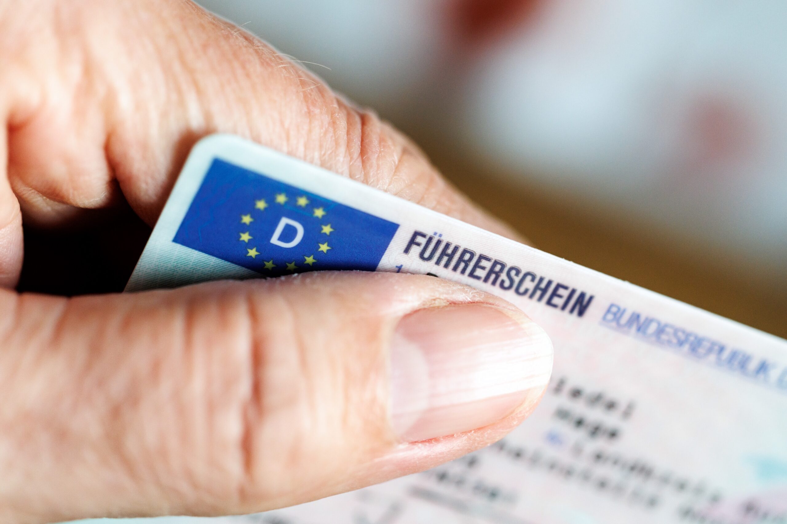 Eine Seniorin hält einen Führerschein in der Hand.