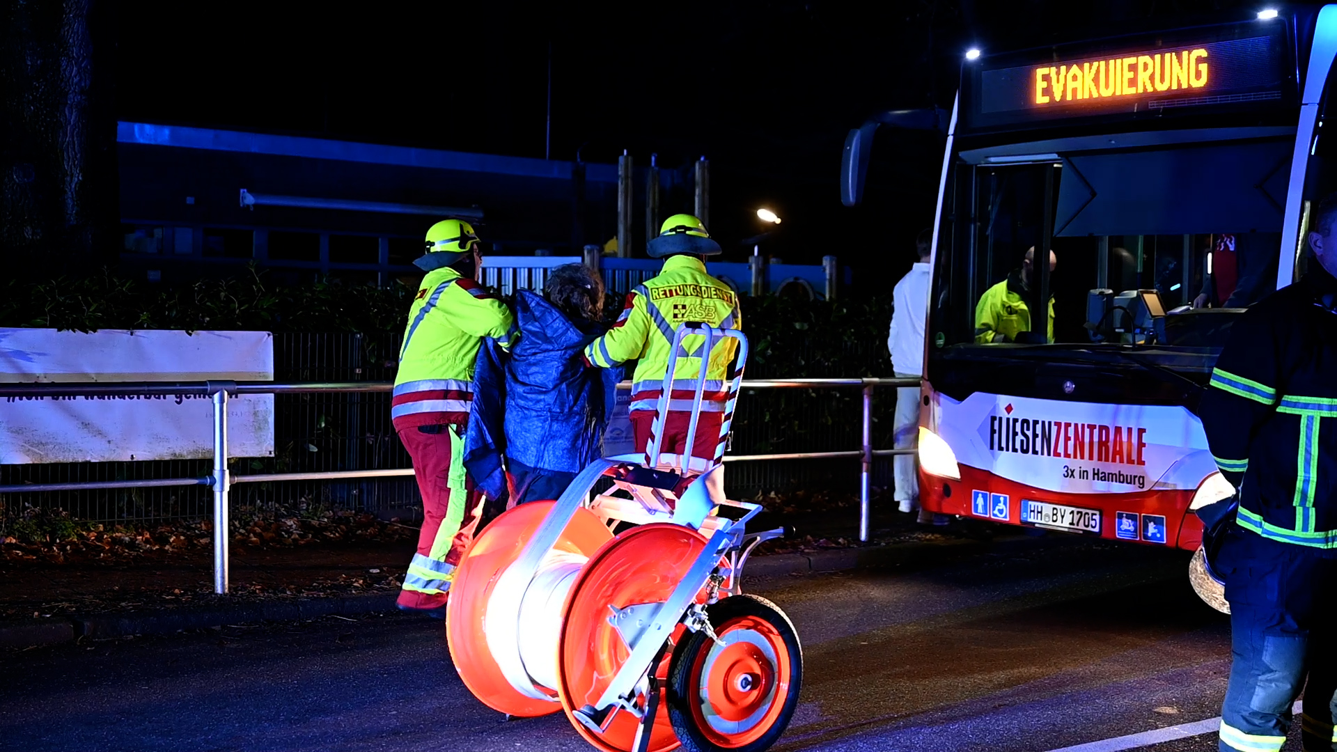 Kräfte des Rettungsdienstes bringen eine Person zur Versorgung zu einem bereitgestellten Bus.
