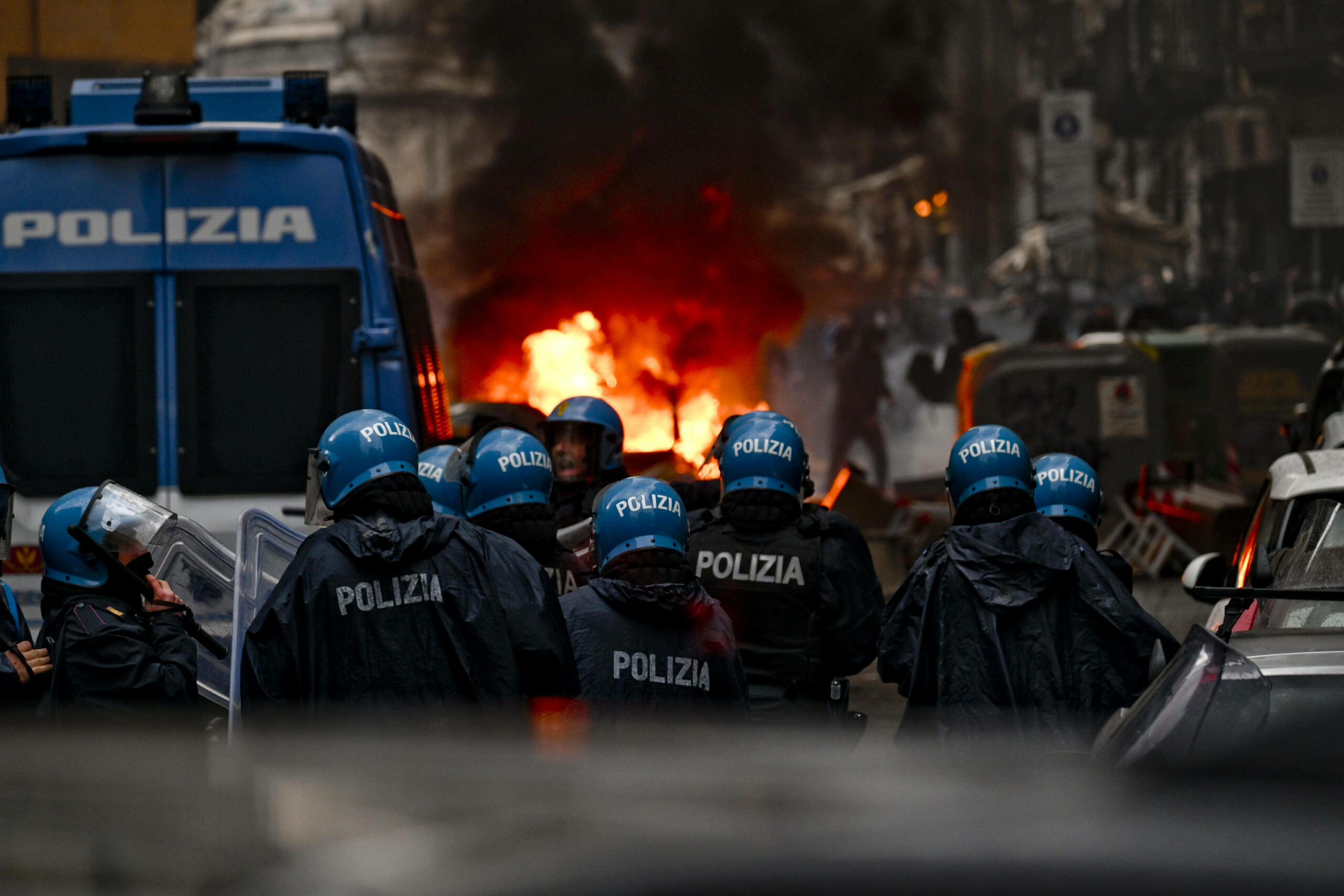 Neapolitanische Polizisten stehen in der Innenstadt vor brennenden Autos und randalierenden Eintracht-Frankfurt-Fans.