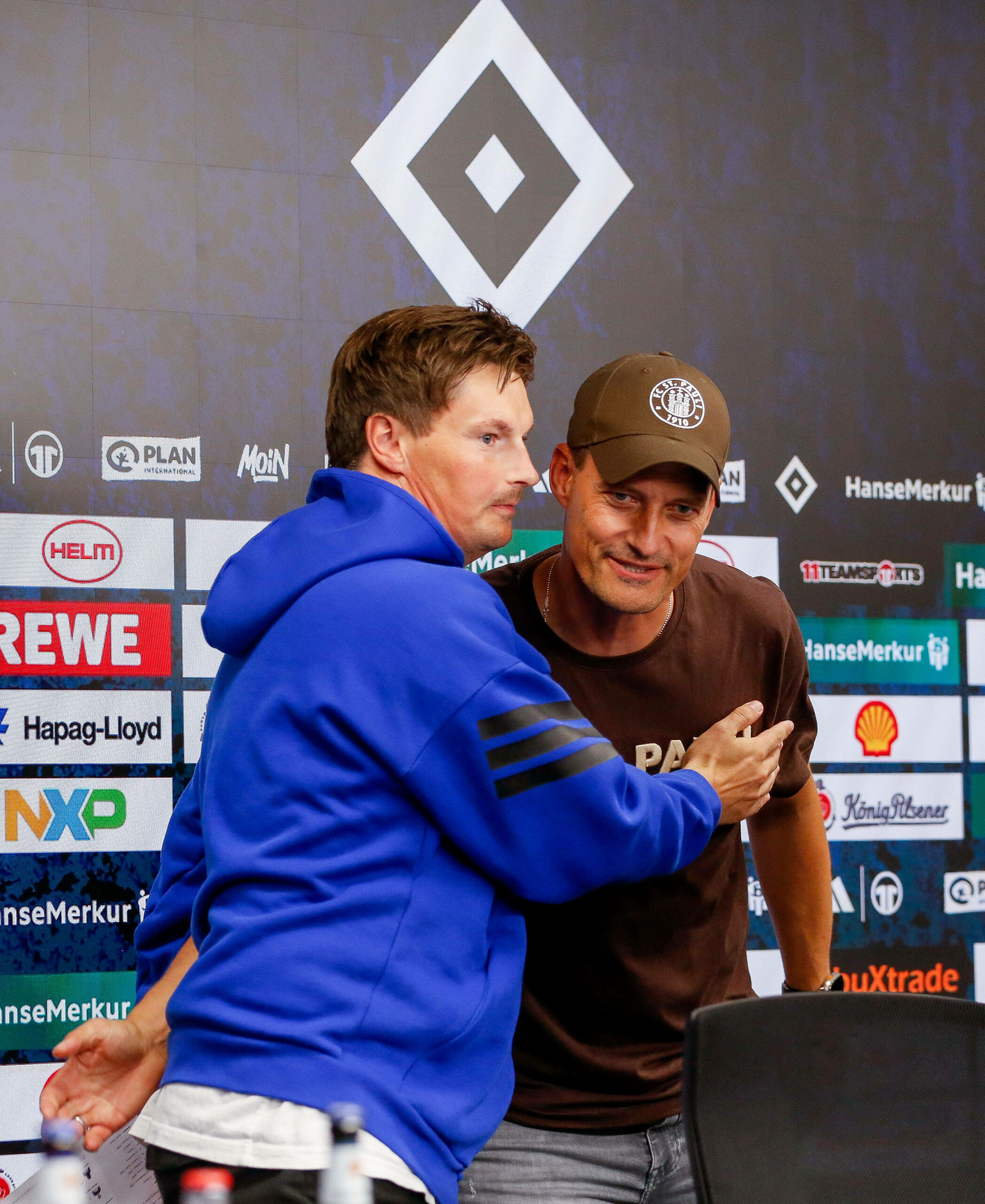 Merlin Polzin und Alexander Blessin umarmen sich auf der Pressekonferenz