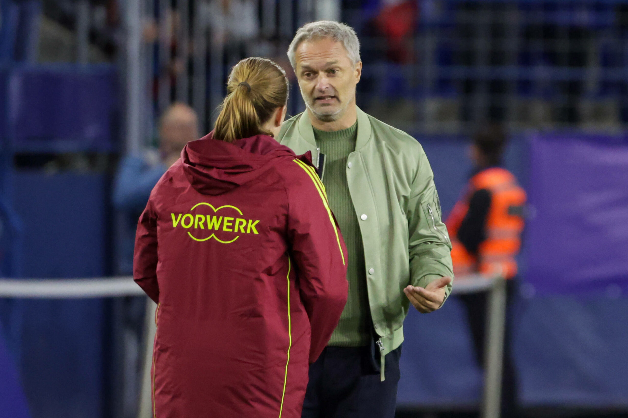 Christian Wück klatscht mit einer Spielerin ab, die mit dem Rücken zur Kamera steht.