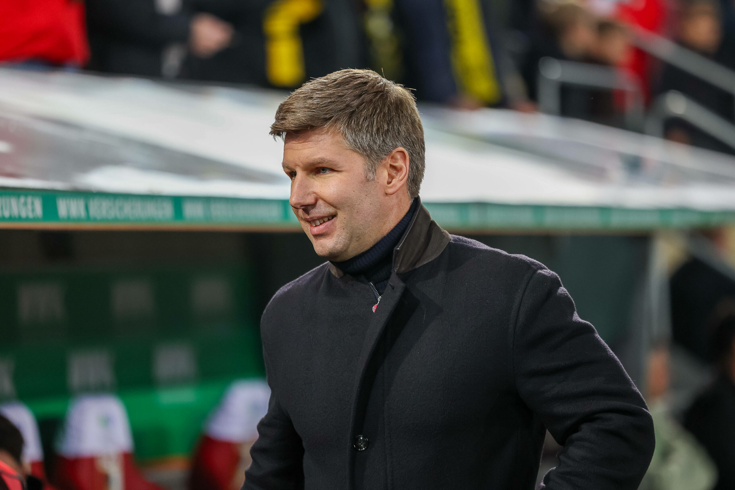 Thomas Hitzelsperger im Mantel in der WWK-Arena in Augsburg