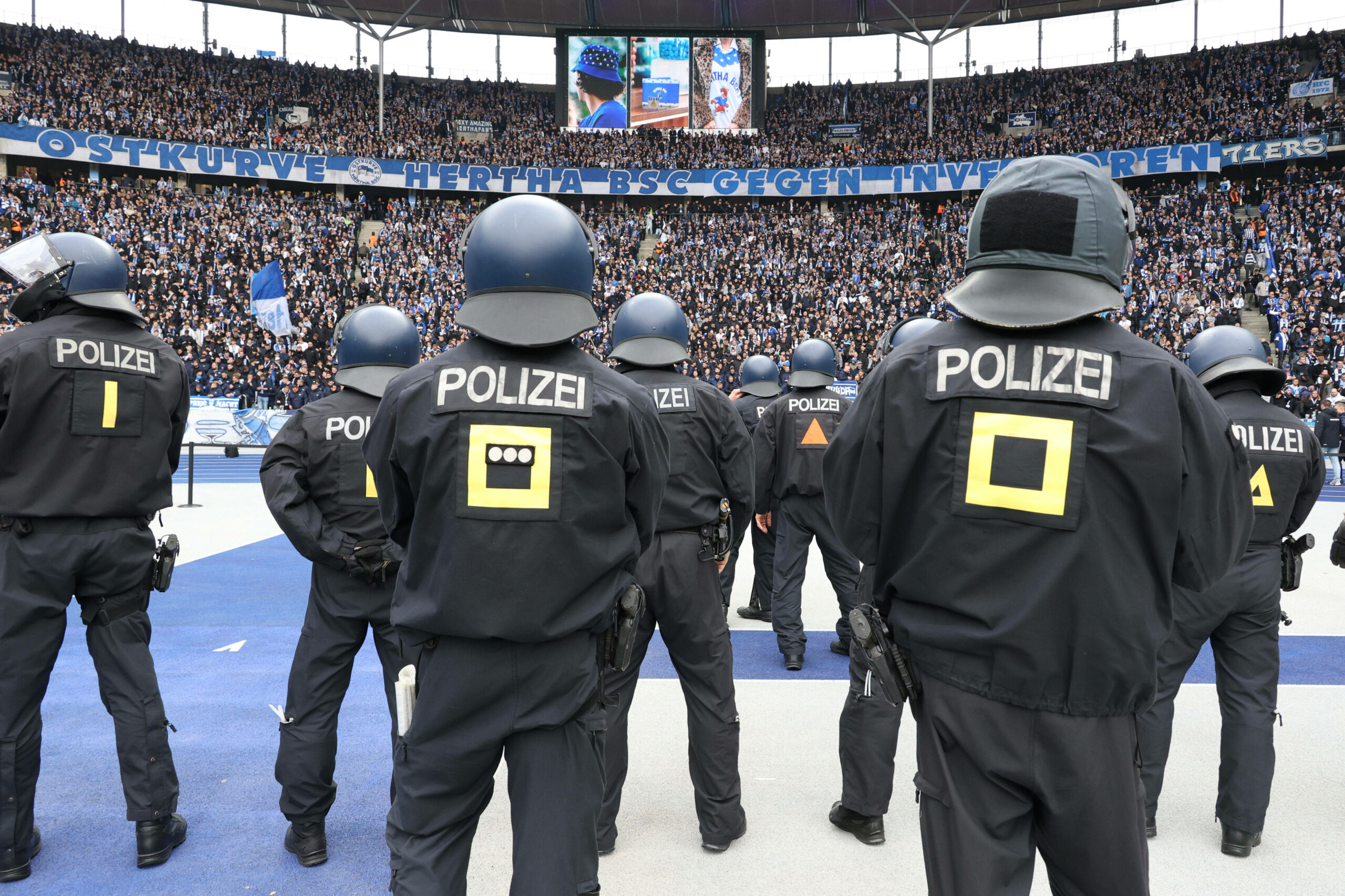 Polizisten stellen sich, im Innenraum, vor der Ostkurve des Olympiastadions auf