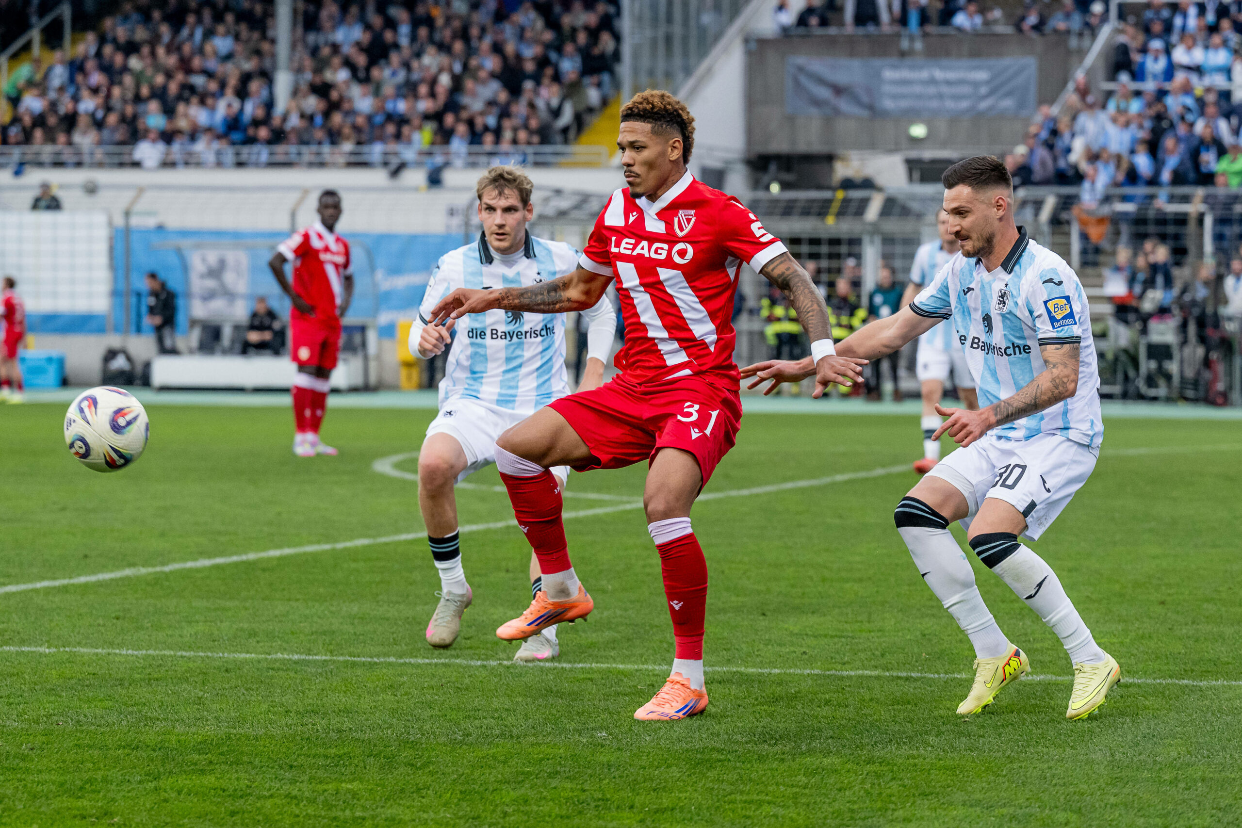 Clemens Lippmann (TSV 1860 München, l.), Justin Butler (FC Energie Cottbus, m.) und Maximilian Wolfram (TSV 1860 München, r.) schauen auf den Ball