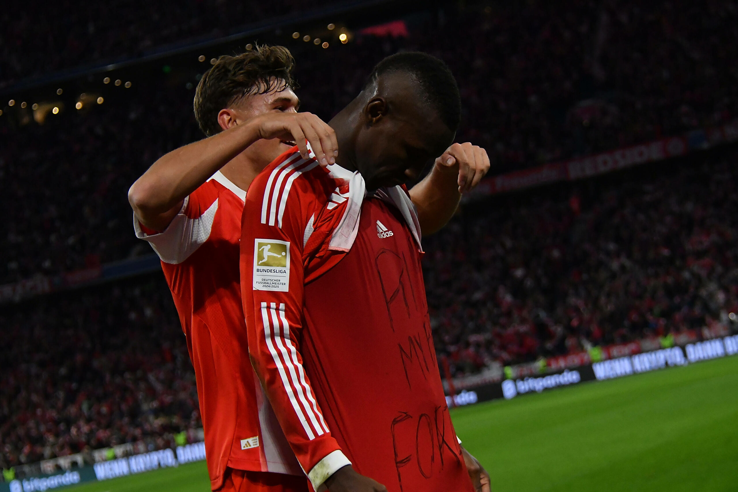 Tom Bischof (l.) jubelt gemeinsam mit Nicolas Jackson (r.), dieser zeigt, auf seinem Unterzieh-Shirt, eine Botschaft für einen verstorbenen Freund aus dem Senegal „RIP, My Bro Fokzo“