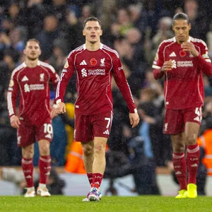 Alexis Mac Allister (l.), Florian Wirtz (m.) und Virgil van Dijk (r.) vom FC Liverpool, stehen bedient im Regen von Manchester