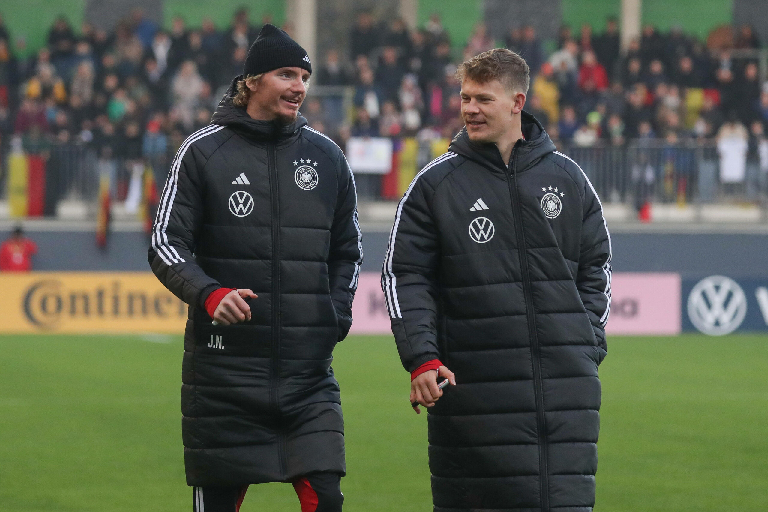 Nick Woltemade (l.) und Alexander Nübel (r.) in dicken Mänteln des DFBs auf dem Weg Unterschriften zu geben.