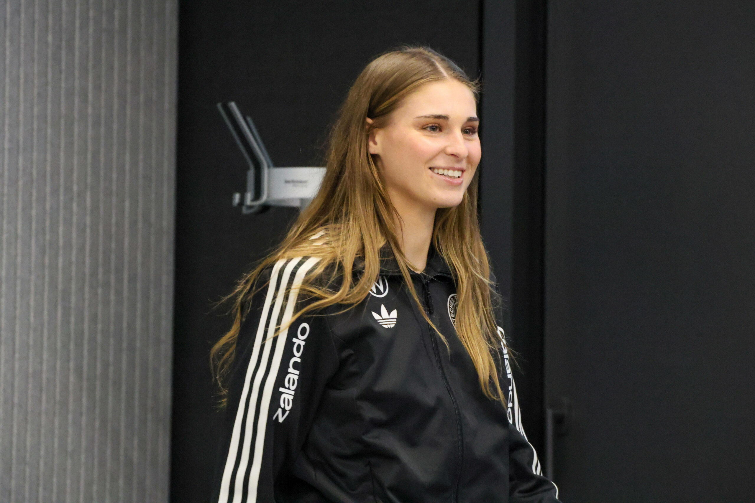 Jule Brand lächelnd auf dem Weg zur Pressekonferenz