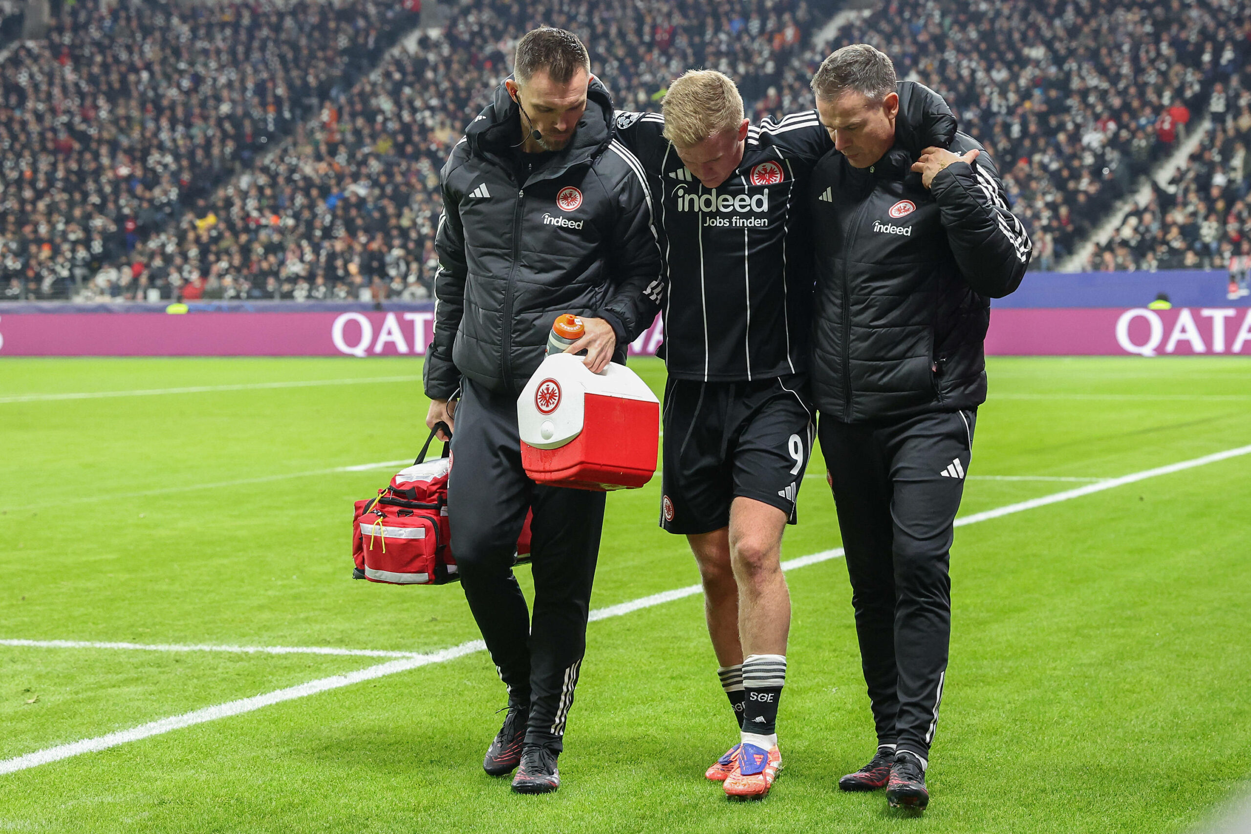 Eintracht-Stürmer Jonathan Burkardt verletzt sich gegen Atalanta Bergamo und wird von zwei Betreuern gestützt