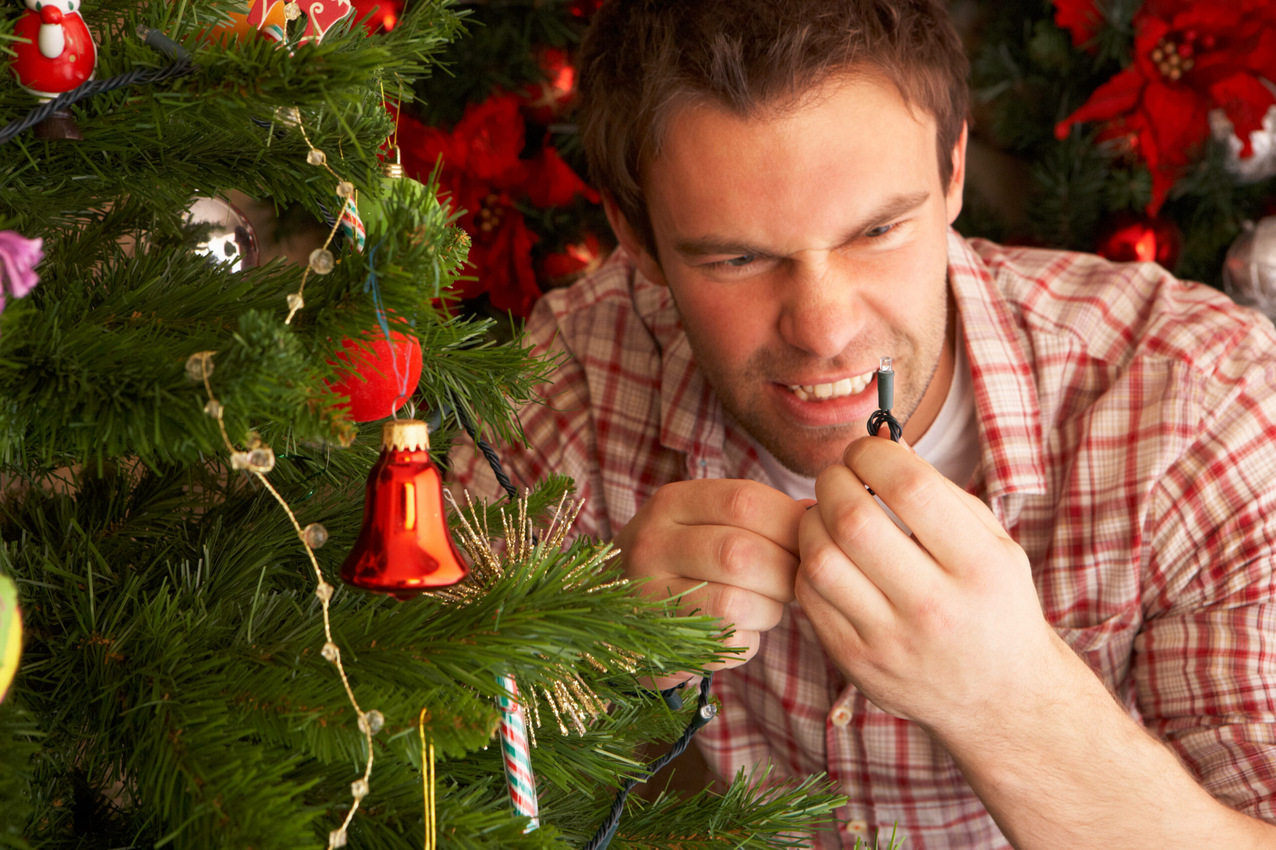 Mann mit ärgerlichem Gesicht am Weihnachtsbaum