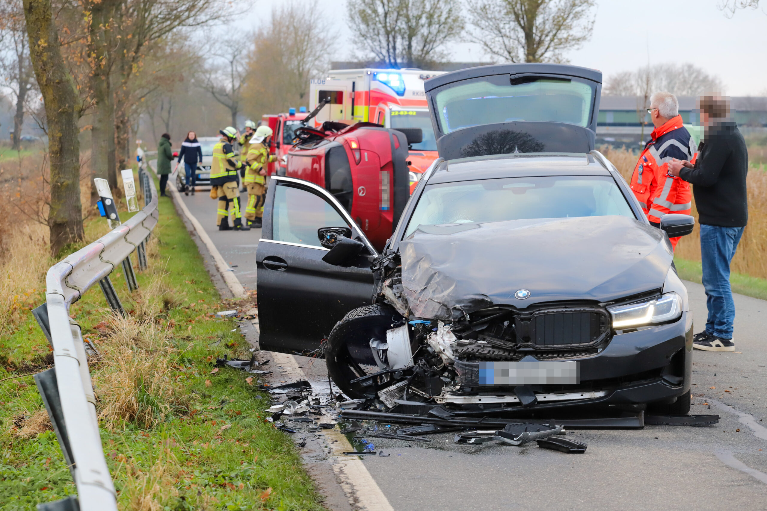 Ein verunfalltes Auto steht auf einer Straße. Im Hintergrund steht ein Rettungswagen.