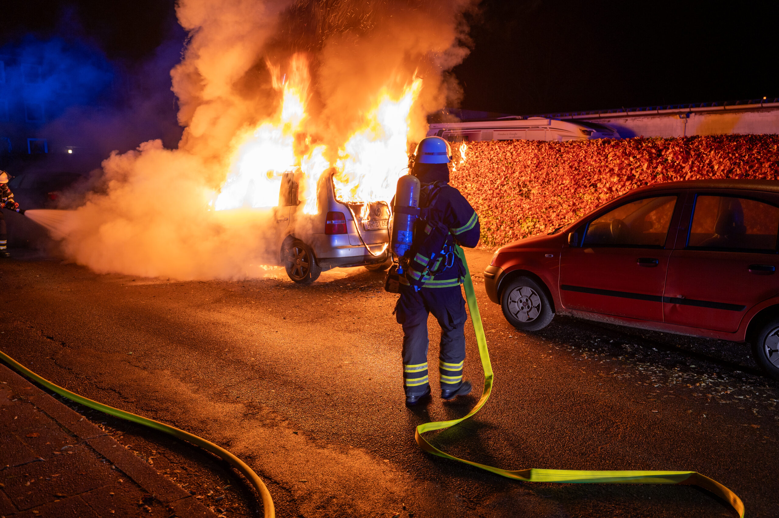 Ein Feuerwehrmann löscht ein brennendes Auto im Cottaweg.