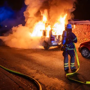 Ein Feuerwehrmann löscht ein brennendes Auto im Cottaweg.