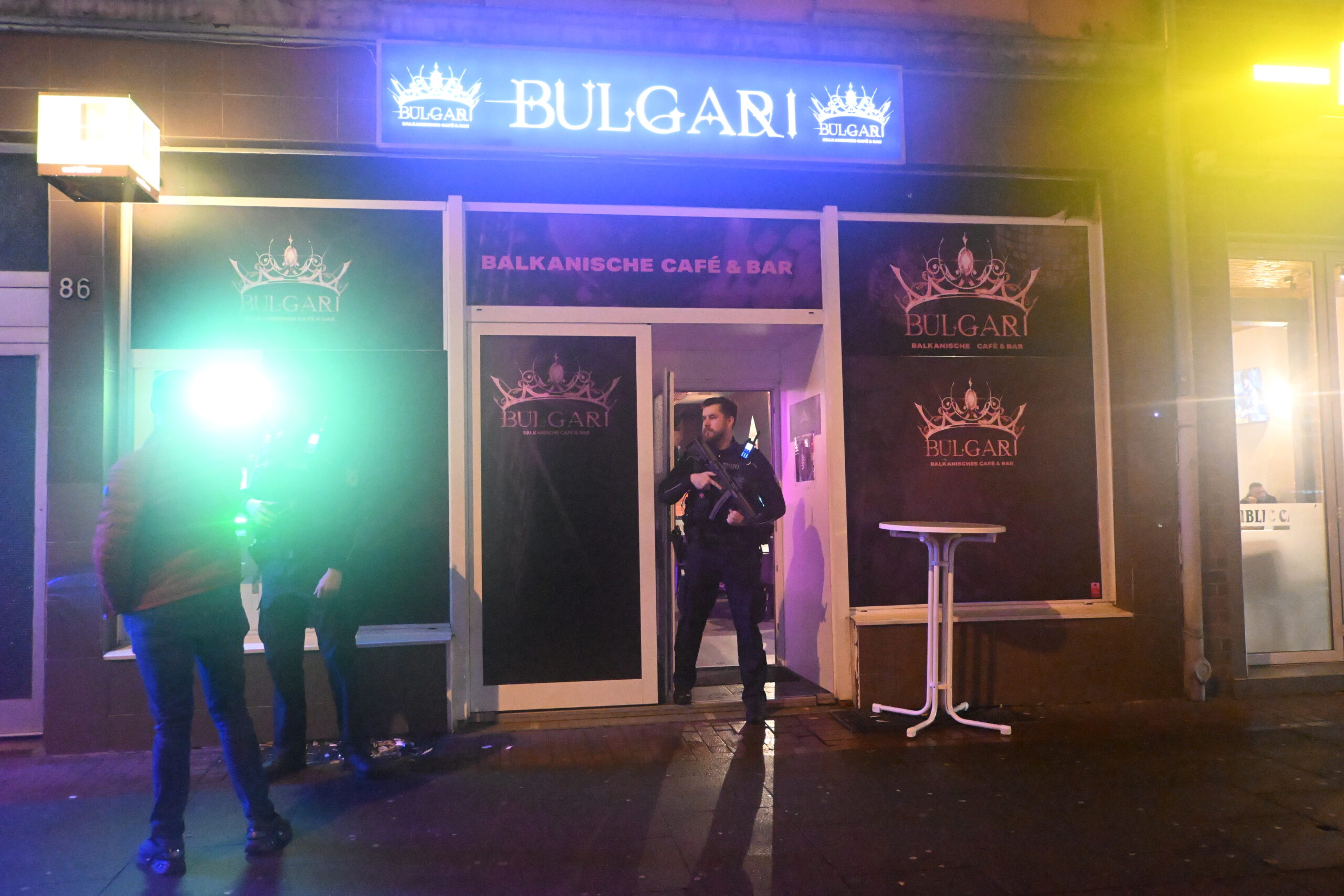 Ein Polizist mit Maschinenpistole sichert den Eingang einer Kneipe.