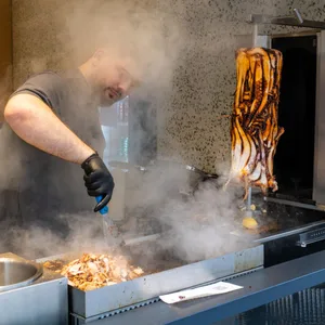 Ein Mitarbeiter bereitet im Restaurant „Pescobar“ das Fleisch für einen Calamari-Kebab zu.