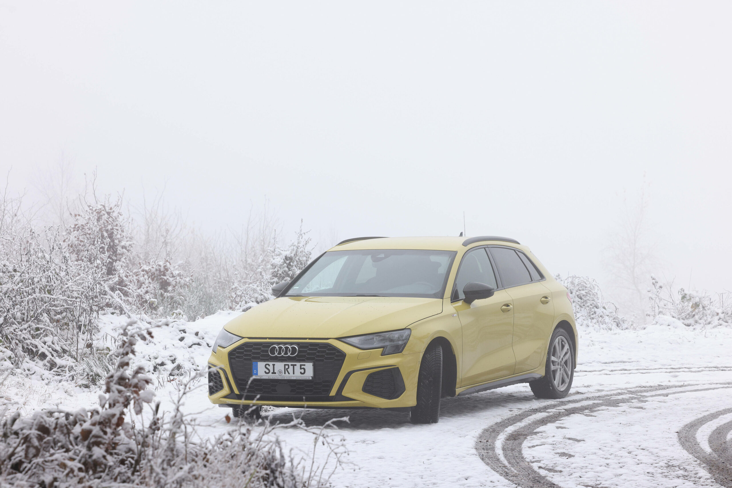 Ein gelber Audi A3 steht auf einem Parkplatz im Schnee.