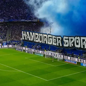 HSV-Fans zünden auf der Nordtribüne im Volksparkstadion blaue Rauchtöpfe.