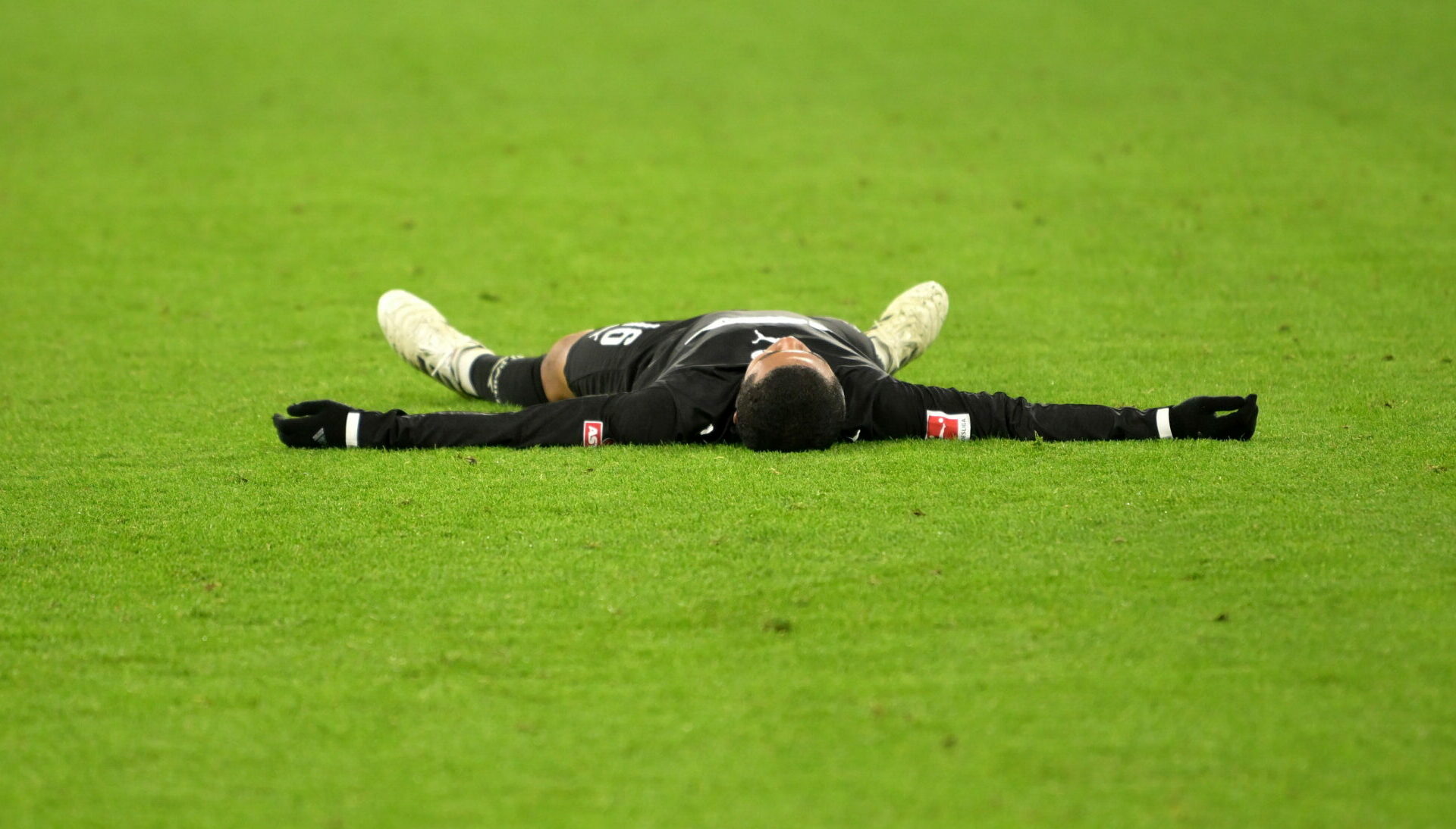 Joel Chima Fujita liegt auf dem Rasen, alle Viere von sich gestreckt