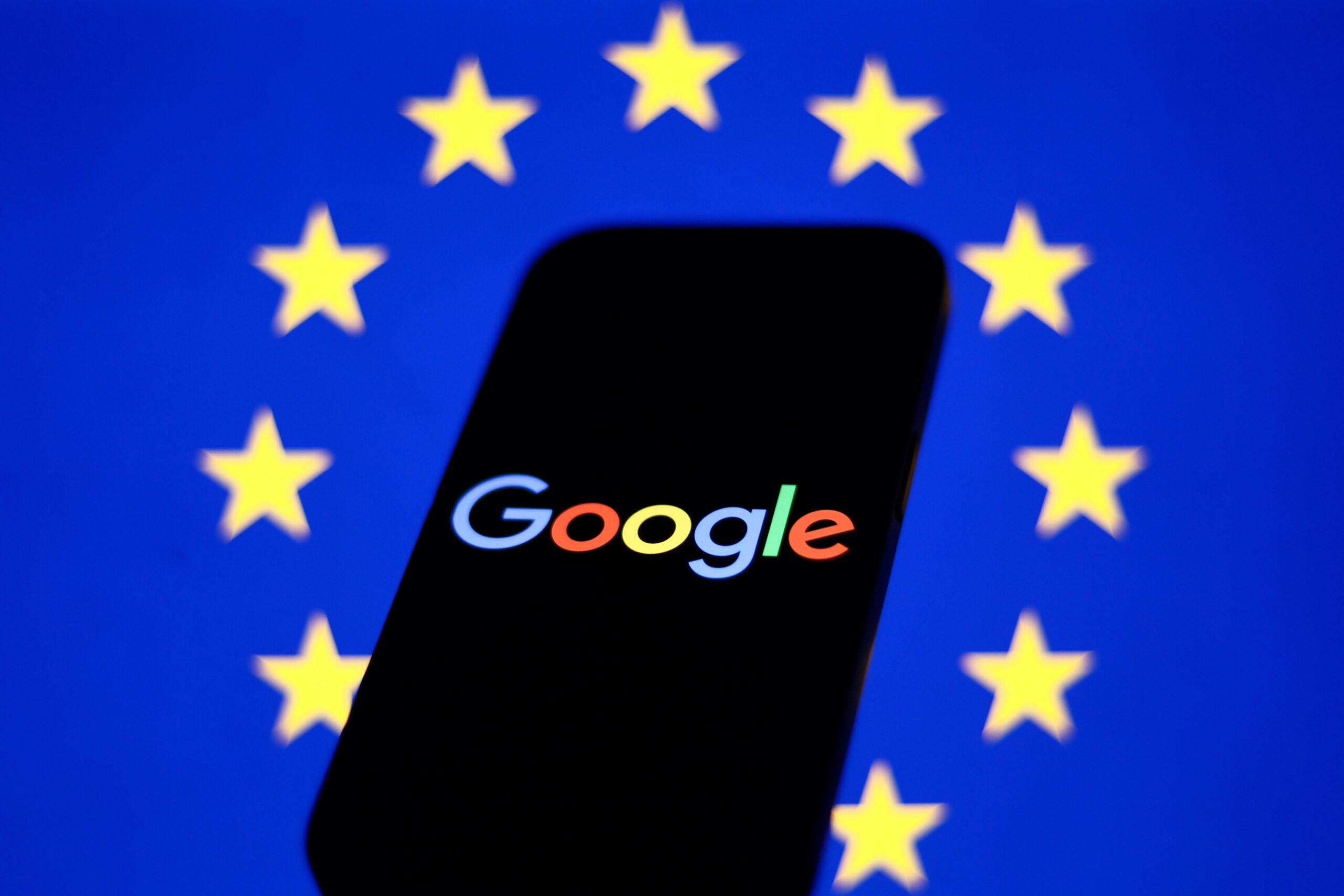 Europäische Flagge hinter einem Handy mit dem Google-Logo
