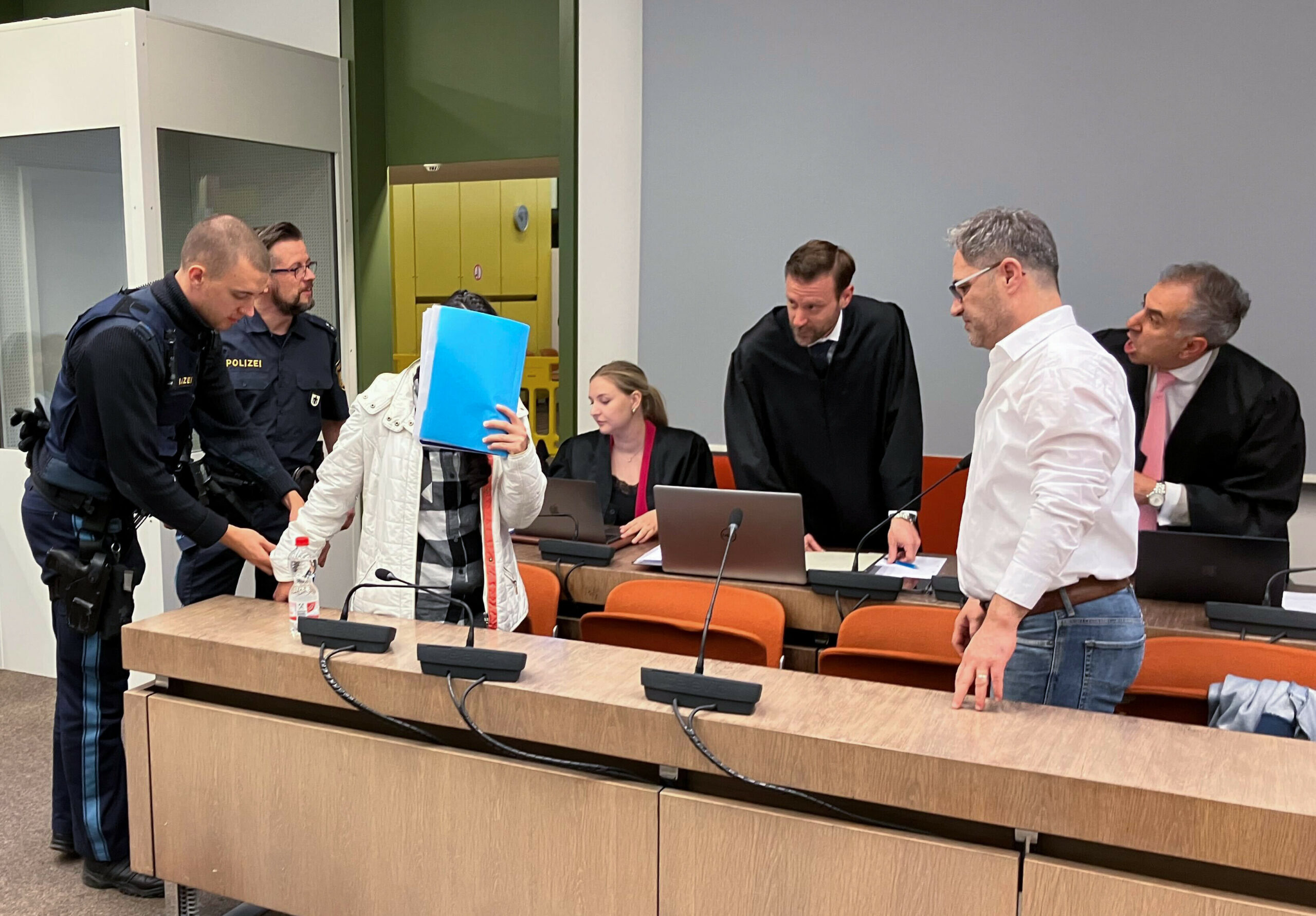 Die wegen Versklavung, Vergewaltigung und Verbrechen gegen die Menschlichkeit angeklagte irakische Frau und und ihr mitangeklagter Mann stehen im Saal des Münchener Oberlandesgerichts.