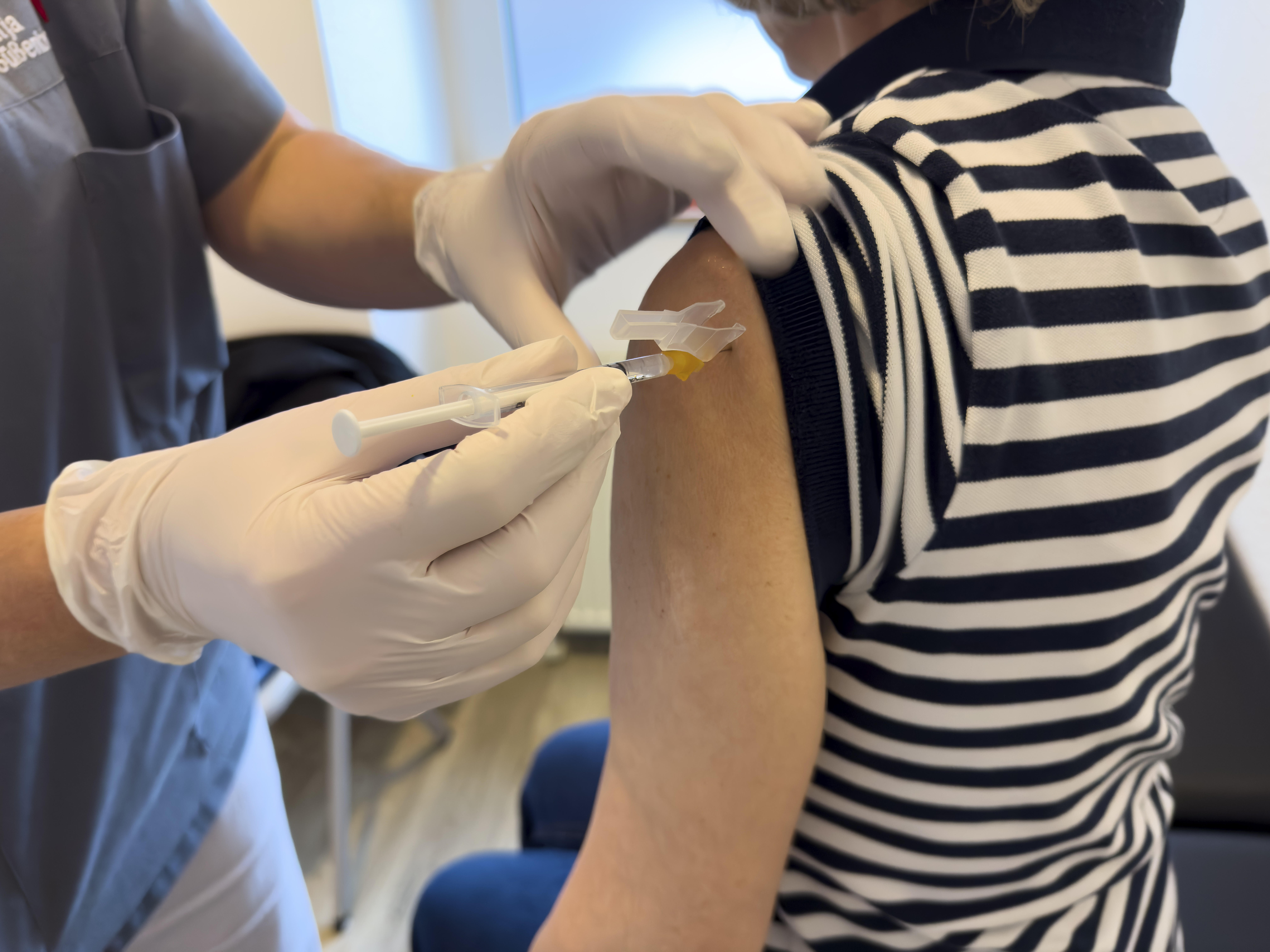 Frau bekommt eine Spritze in den Oberarm