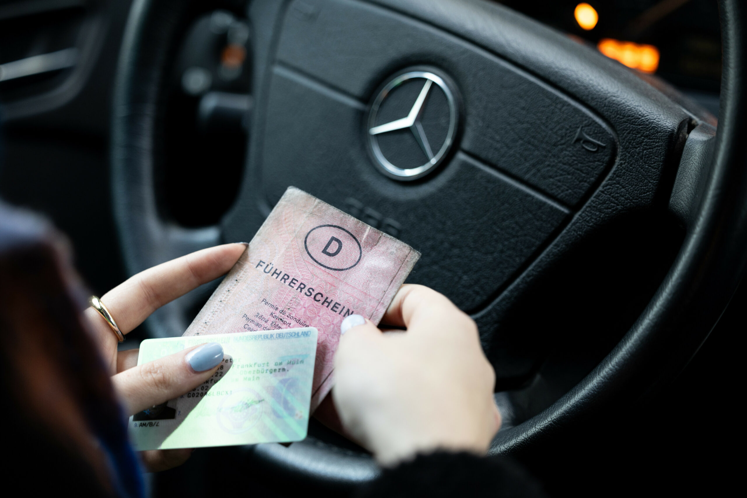 Eine Frau hält einen neuen und einen alten Führerschein in der Hand.