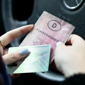 Eine Frau hält einen neuen und einen alten Führerschein in der Hand.