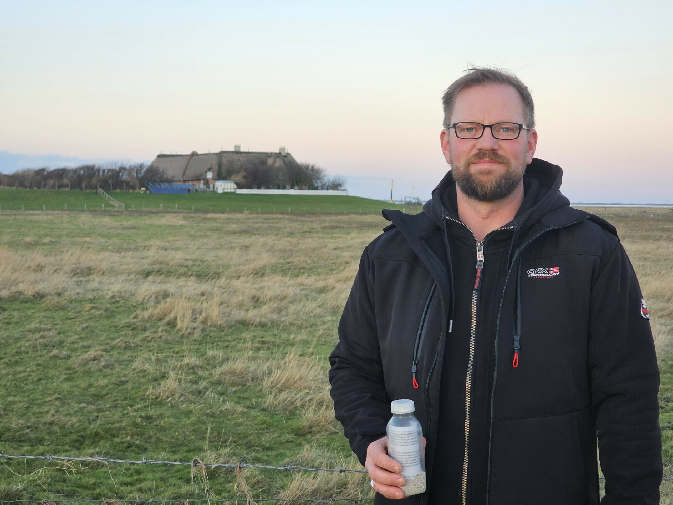Mann mit einer Flasche auf einer Hallig