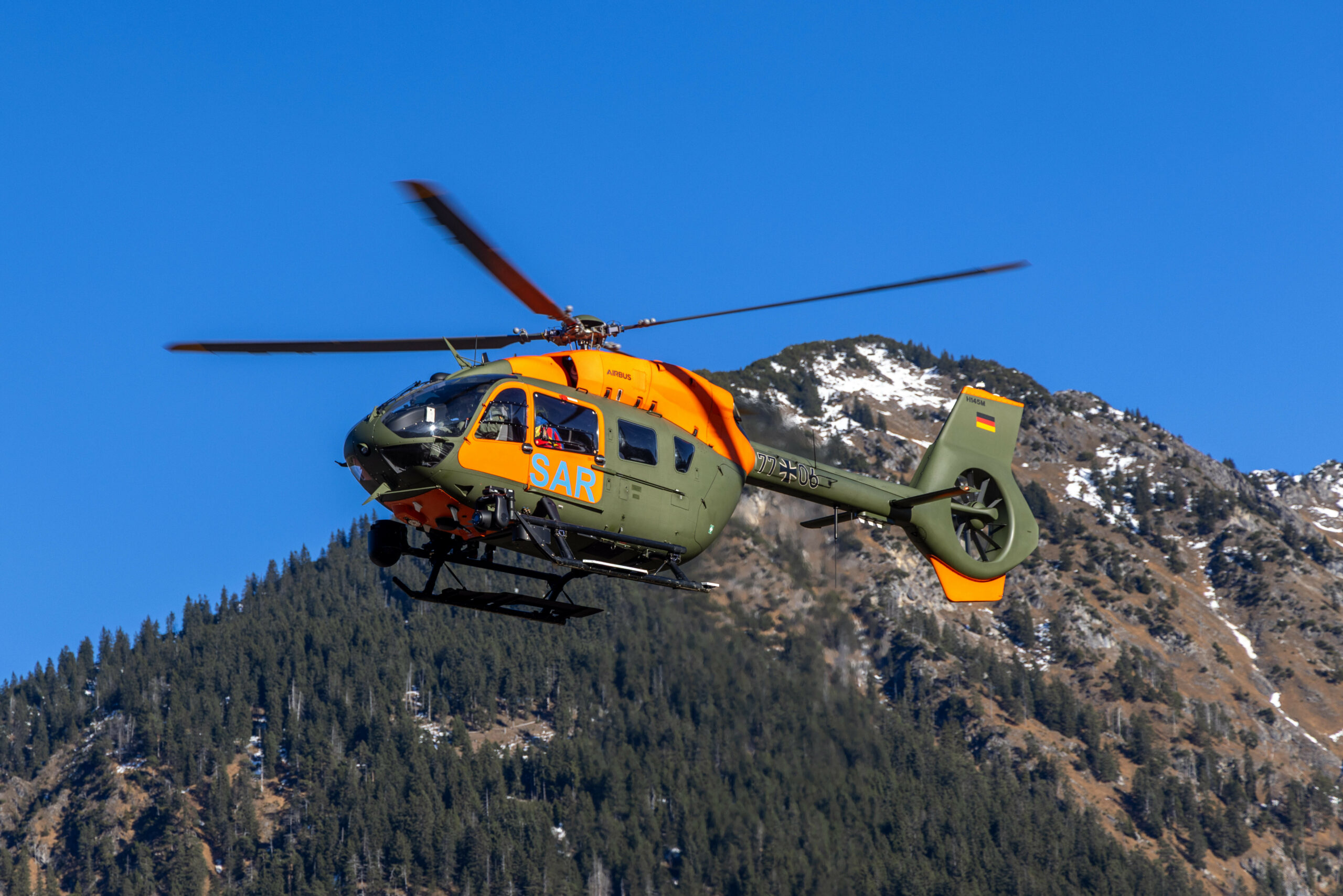 Ein Hubschrauber der Bundeswehr fliegt vor Bergen.