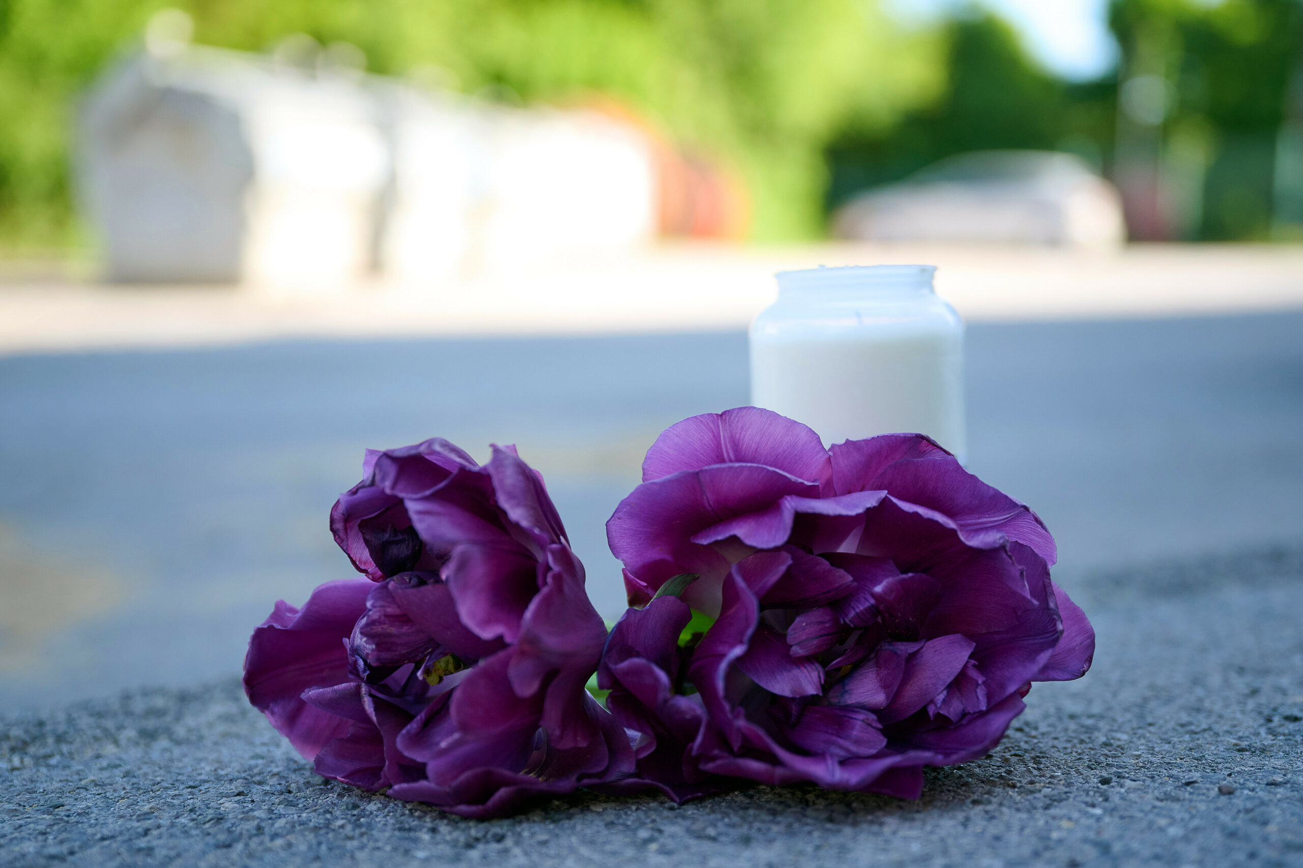 Blumen und eine Kerze liegen auf einem Schotterplatz vor dem Eingang zu einem Spielplatz. Auf einem Spielplatz im Sauerland soll in der Nacht auf den 10. Mai ein 17-Jähriger einen 14-Jährigen erstochen haben.