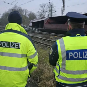Einsatzkräfte der Bundespolizei stehen nach dem Zugunglück bei Elze an den Gleisen neben umgekippten Schüttgutwagen.