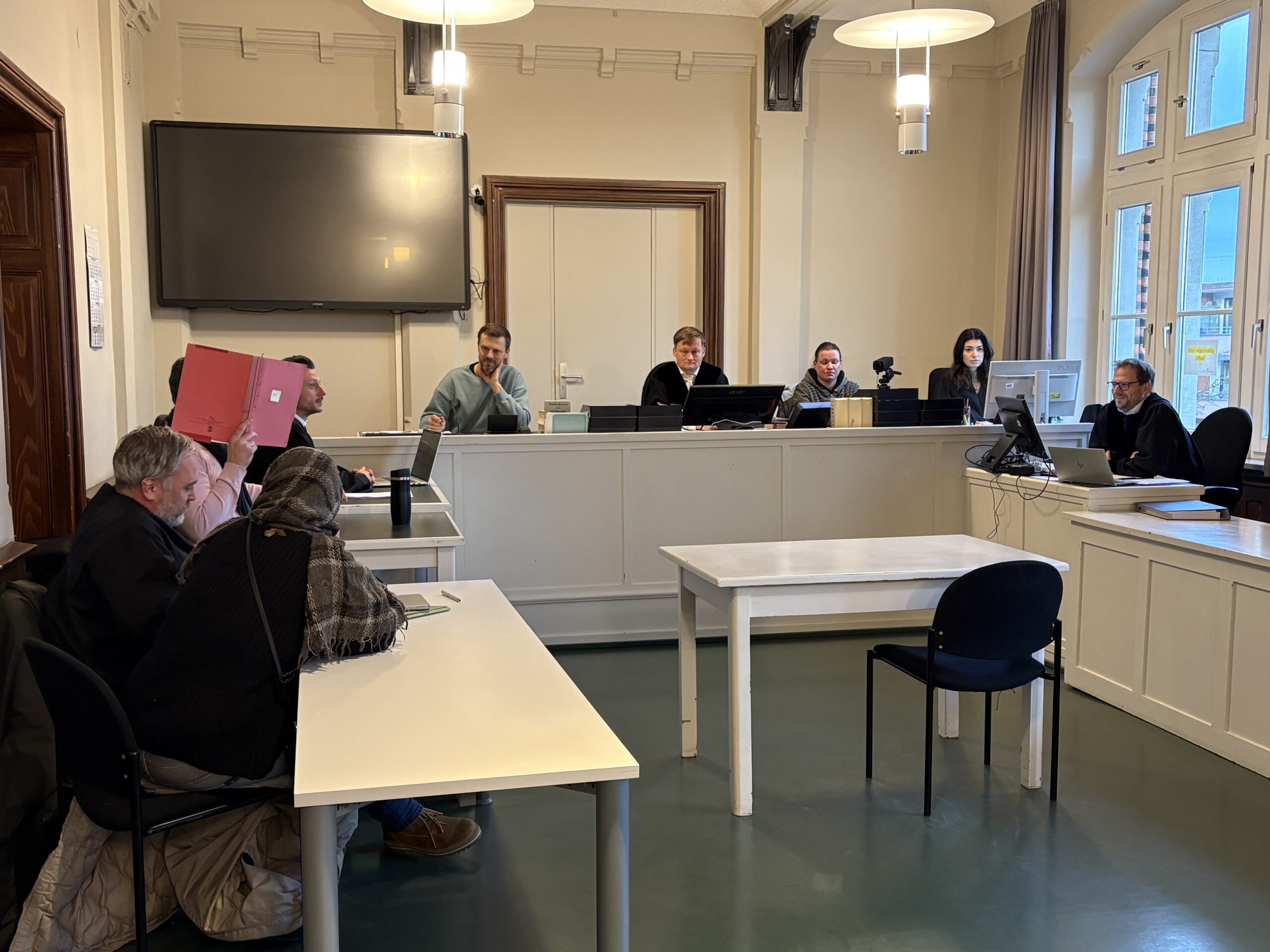 Amtsgericht Harburg: Die Angeklagte und ihr mitangeklagter Ehemann verbergen ihre Gesichter hinter Aktenmappen.