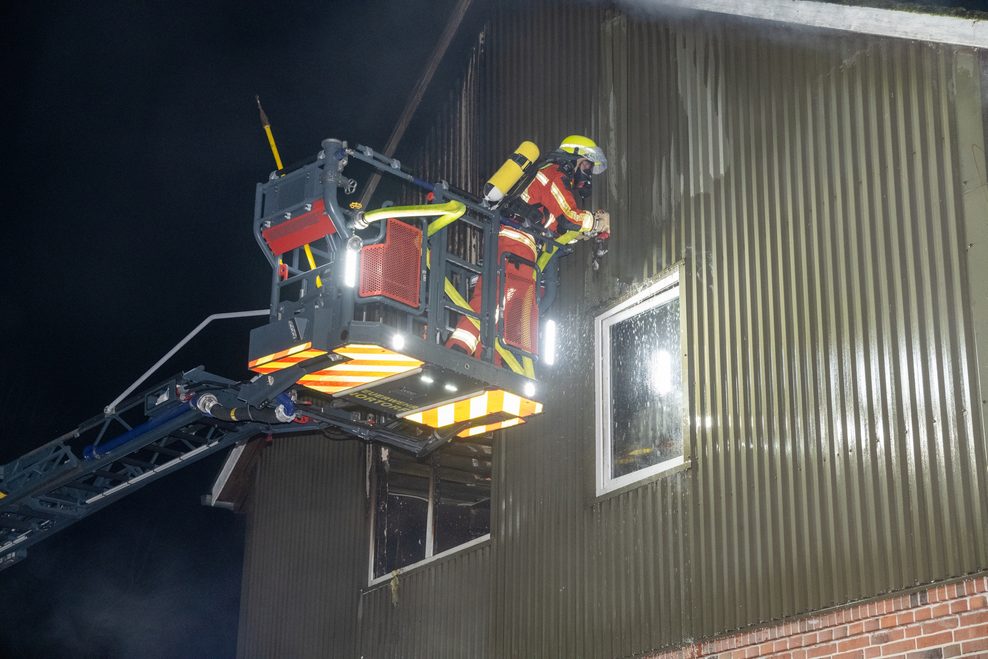 Feuerwehrmann auf einer Drehleiter beim Löschen des Hauses in Emkendorf.