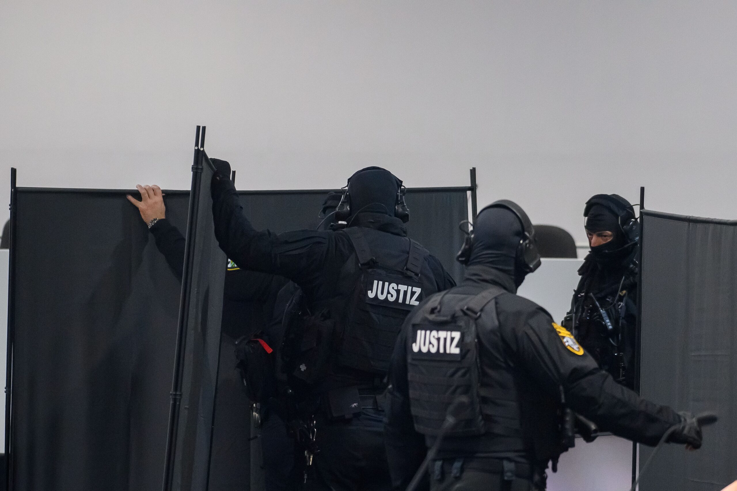 Justizbeamte stellen im Gerichtssaal in Magdeburg probeweise Sichtschutzwände auf.