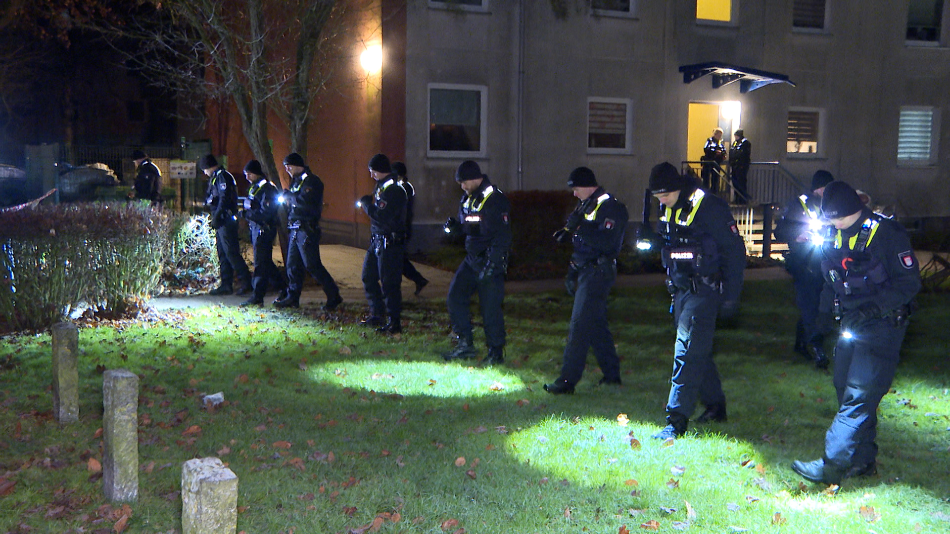 Polizisten suchen das Umfeld des Tatorts nach der Mordwaffe ab.