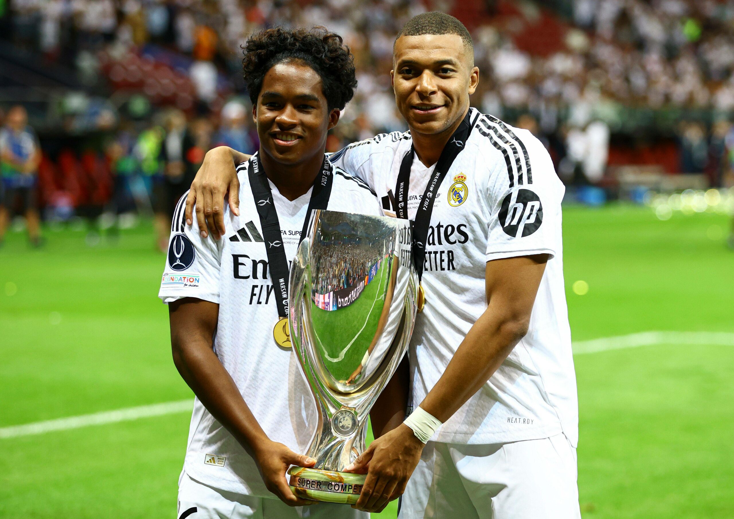 Endrick und Kylian Mbappé halten zusammen einen Pokal und lächeln