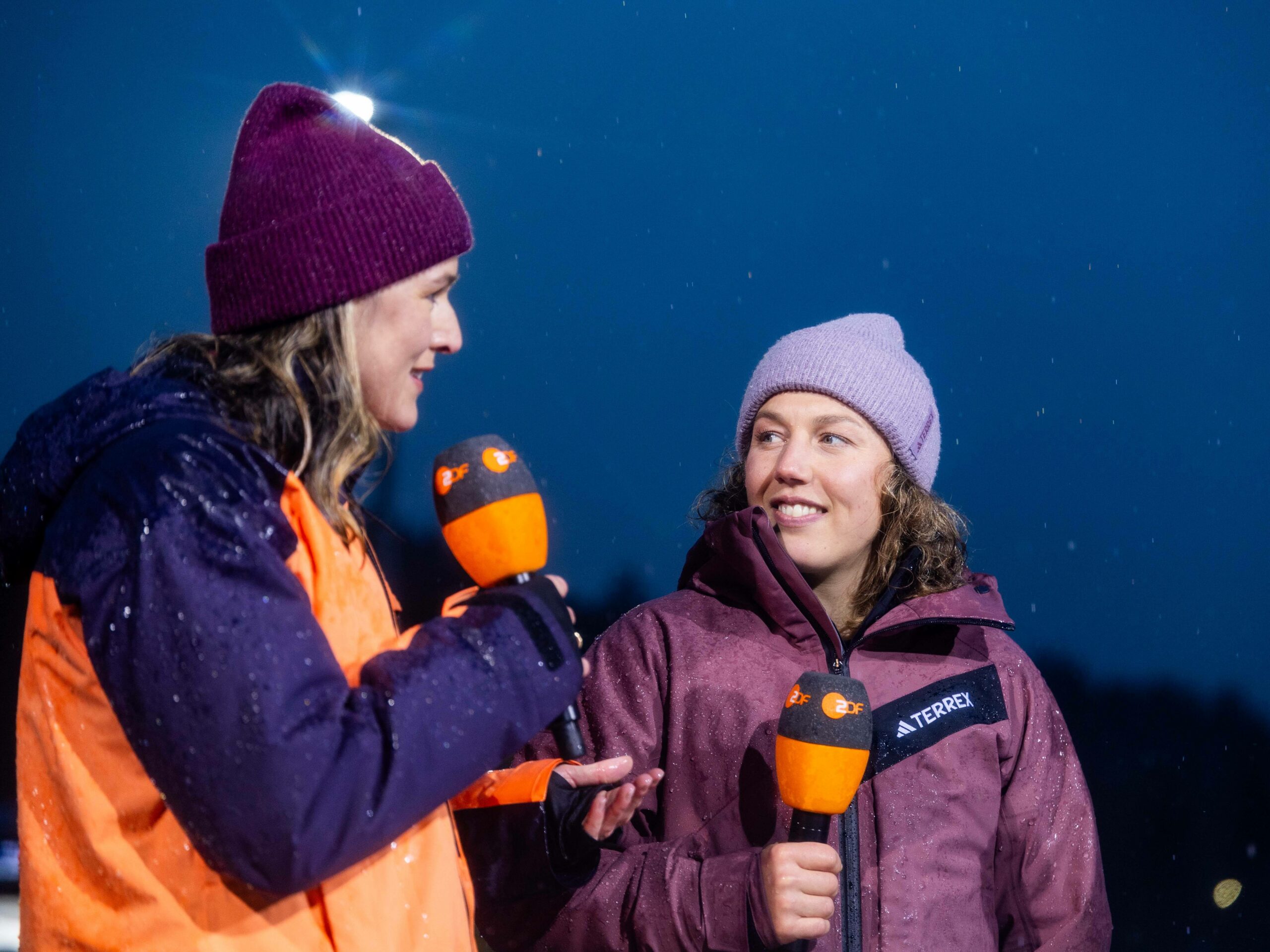 Die ehemaligen Biathletinnen Denise Herrmann-Wick und Laura Dahlmeier schauen glücklich mit Mikrofon in der Hand