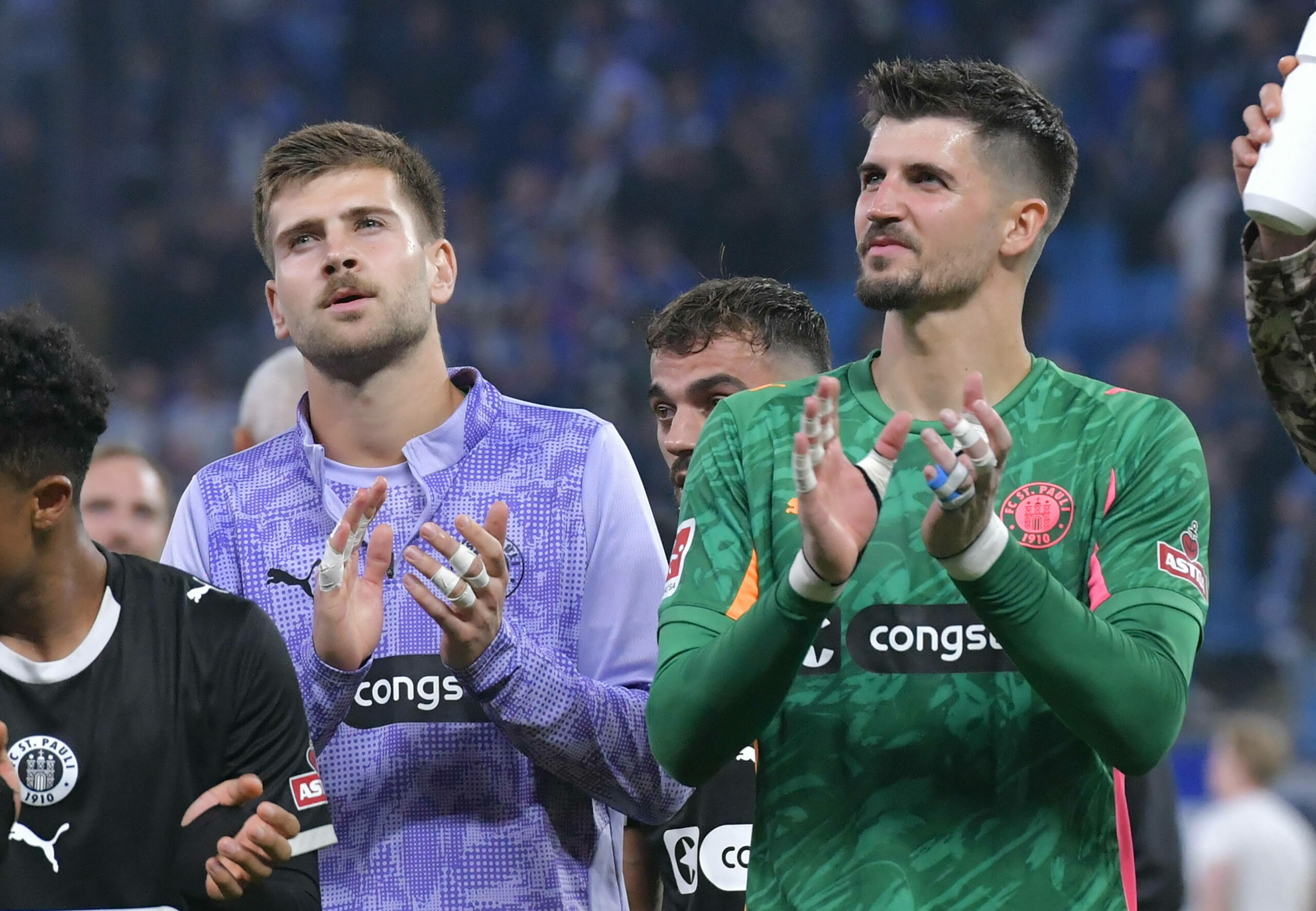 St. Paulis Torhüter Nikola Vasilj und Ben Voll stehen nebeneinander und applaudieren für die Fans